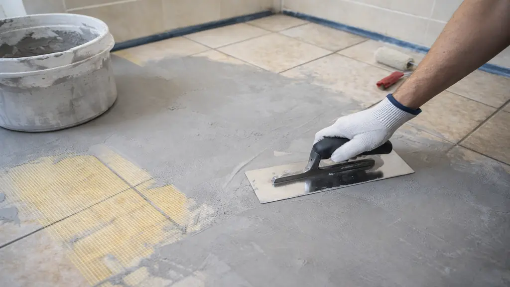 Béton ciré sur carrelage avec application au platoir inox sur sol carrelé, préparation avec treillis de renfort et primaire d’accrochage