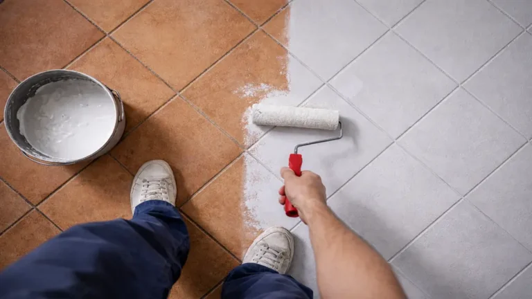Peindre un sol carrelé avec une peinture blanche appliquée au rouleau sur un carrelage en terre cuite, préparation et rénovation du sol intérieur